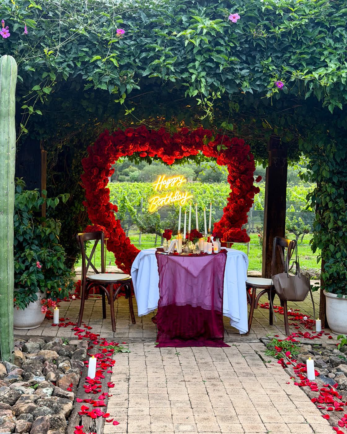 Corazón de rosas rojas con letrero Happy Birthday y mesa decorada en viñedo